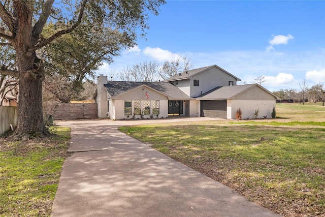 view of front of property with a front lawn, driveway, fence, an attached garage, and a chimney