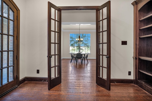 hall with french doors, hardwood / wood-style flooring, an inviting chandelier, and ornamental molding