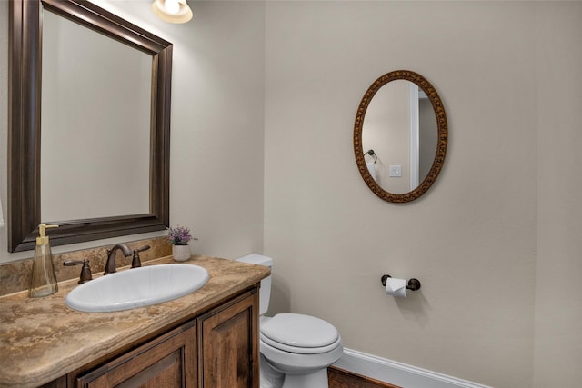 bathroom featuring toilet, vanity, and baseboards