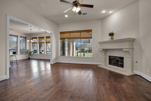 unfurnished living room with a wealth of natural light, visible vents, baseboards, and a glass covered fireplace