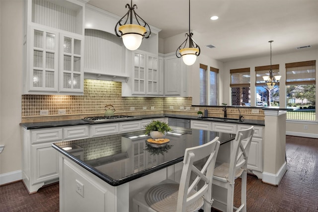 kitchen featuring visible vents, a peninsula, a sink, appliances with stainless steel finishes, and dark countertops