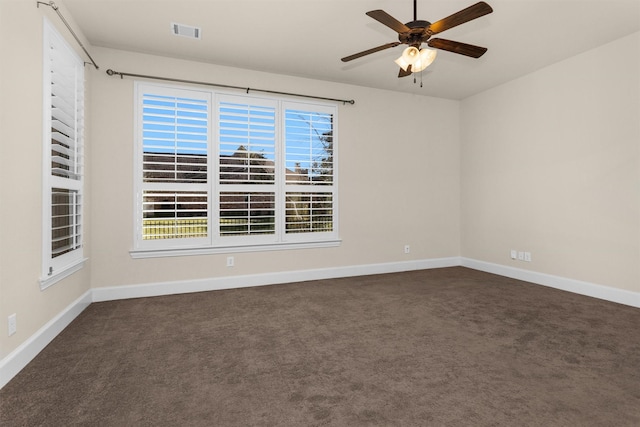 unfurnished room with visible vents, a ceiling fan, baseboards, and dark carpet