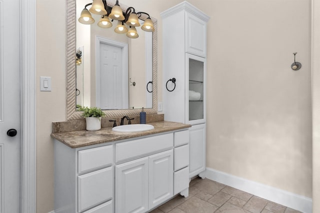 bathroom featuring baseboards, a notable chandelier, and vanity