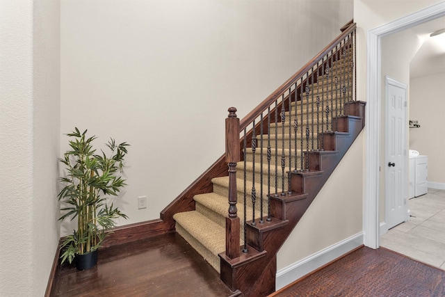 stairway featuring baseboards, wood finished floors, and washer / clothes dryer