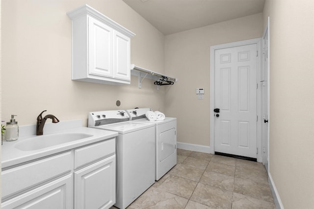 laundry area with washing machine and clothes dryer, cabinet space, baseboards, and a sink