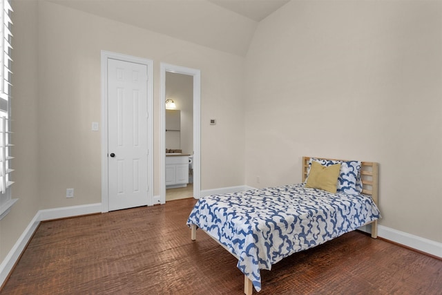 bedroom with ensuite bath, multiple windows, wood finished floors, and baseboards