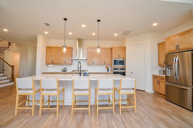 kitchen with visible vents, light wood finished floors, light countertops, appliances with stainless steel finishes, and wall chimney exhaust hood