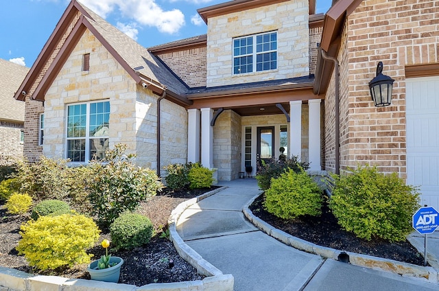 doorway to property with brick siding and a shingled roof