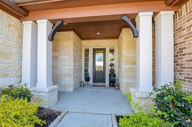 entrance to property with stone siding, brick siding, and covered porch