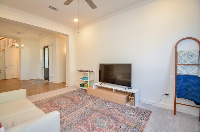 living room featuring visible vents, baseboards, ornamental molding, and ceiling fan with notable chandelier