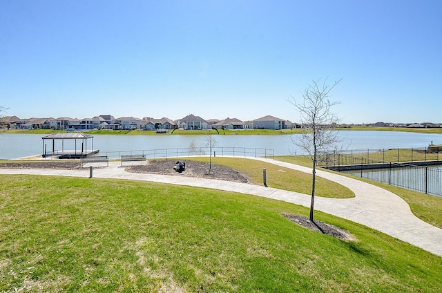 view of dock featuring a residential view, a water view, a yard, and fence