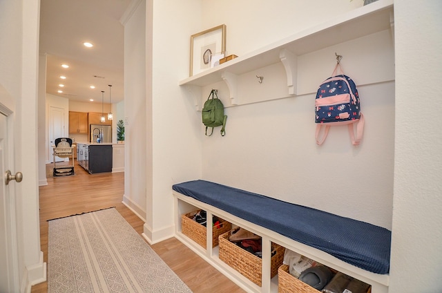 mudroom with recessed lighting, light wood-type flooring, baseboards, and a sink