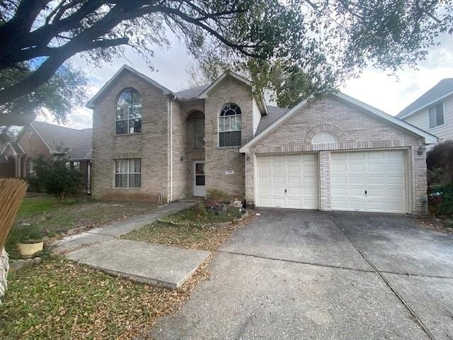 traditional-style house with brick siding, an attached garage, and concrete driveway