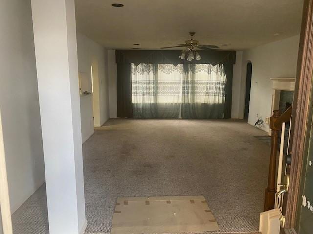 carpeted empty room featuring arched walkways and ceiling fan