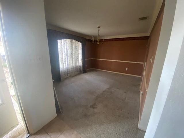 unfurnished dining area with tile patterned floors, visible vents, a chandelier, and carpet flooring