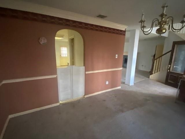 empty room with visible vents, baseboards, arched walkways, stairs, and a notable chandelier