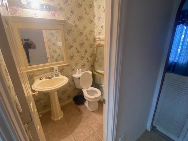 bathroom featuring wallpapered walls, toilet, baseboards, and tile patterned flooring