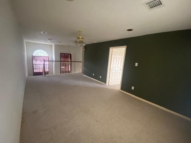 unfurnished room with visible vents, baseboards, and light colored carpet