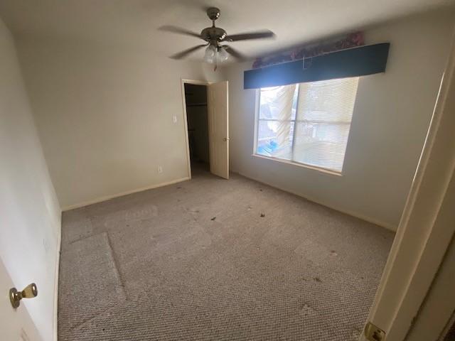 unfurnished bedroom featuring light carpet, baseboards, and ceiling fan