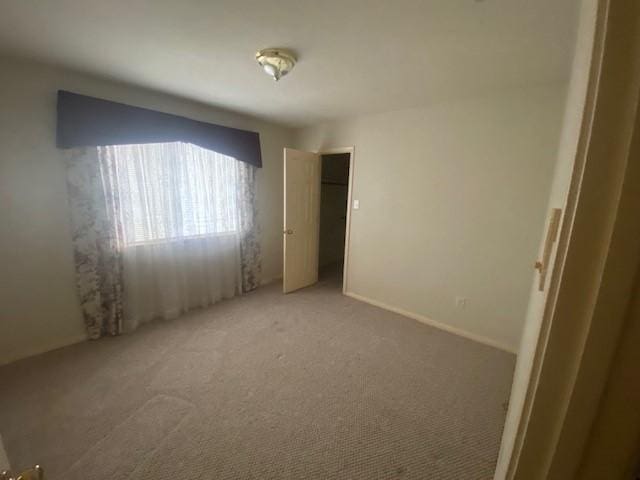 unfurnished bedroom featuring a closet and light colored carpet