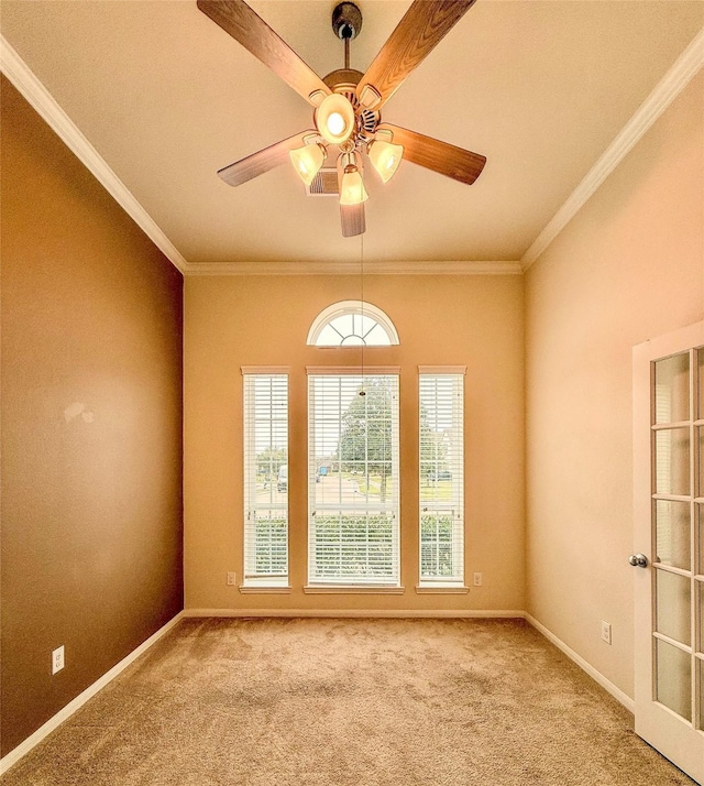 carpeted spare room featuring baseboards, ornamental molding, and a ceiling fan