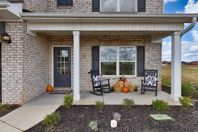 entrance to property featuring brick siding and covered porch