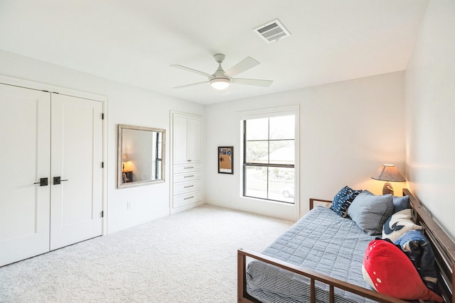 bedroom featuring visible vents, light carpet, ceiling fan, and multiple closets