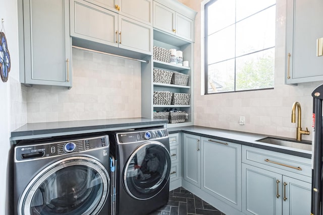 washroom with washer and dryer, cabinet space, and a sink