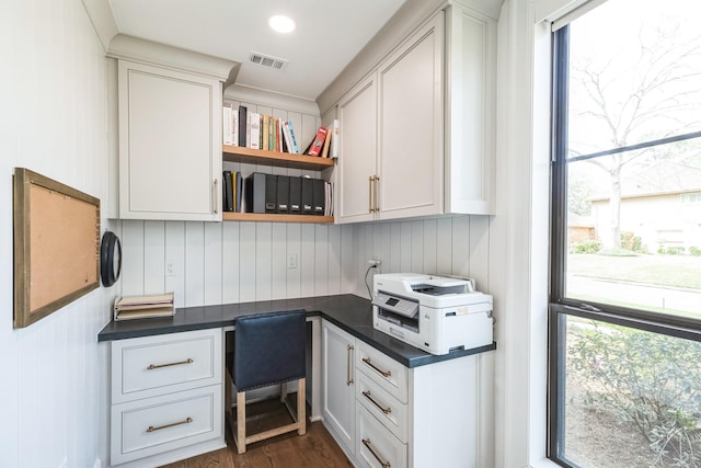 office area with visible vents, dark wood-style flooring, and built in desk