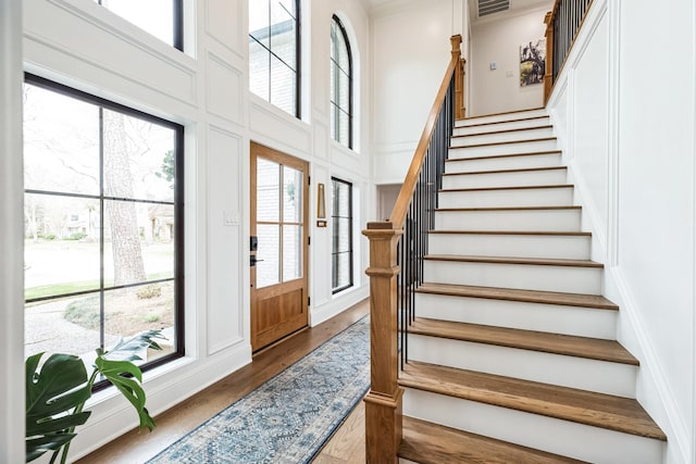 entrance foyer featuring stairway, a high ceiling, wood finished floors, and a decorative wall