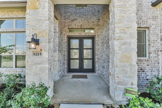 property entrance with french doors, stone siding, and brick siding