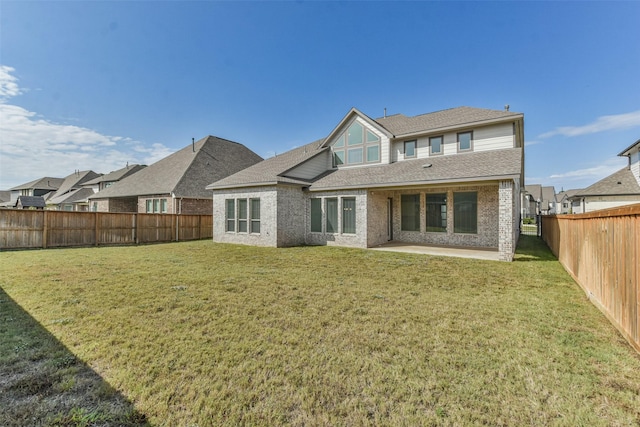 rear view of property featuring a patio, a lawn, brick siding, and a fenced backyard