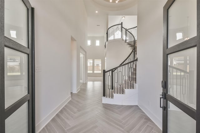 foyer featuring recessed lighting, baseboards, a high ceiling, and stairs