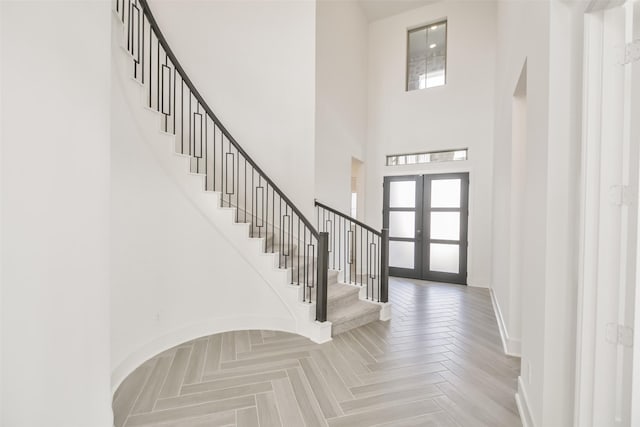 foyer with french doors, baseboards, a towering ceiling, and stairway