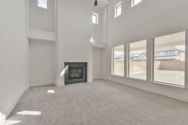 unfurnished living room with a glass covered fireplace, a ceiling fan, baseboards, and carpet floors