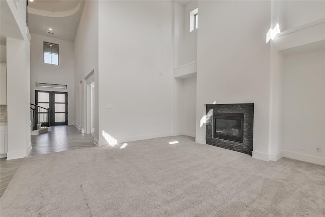 unfurnished living room with a glass covered fireplace, french doors, baseboards, and carpet floors