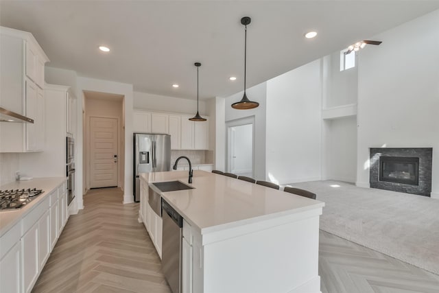 kitchen featuring a sink, stainless steel appliances, open floor plan, and white cabinets