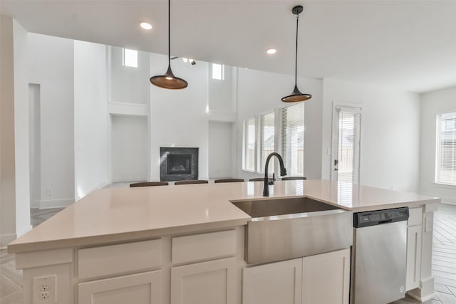 kitchen featuring a fireplace, a sink, light countertops, dishwasher, and open floor plan