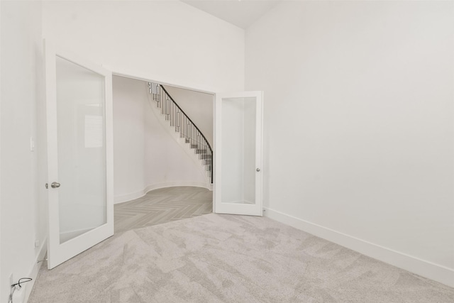 spare room featuring french doors, baseboards, and carpet