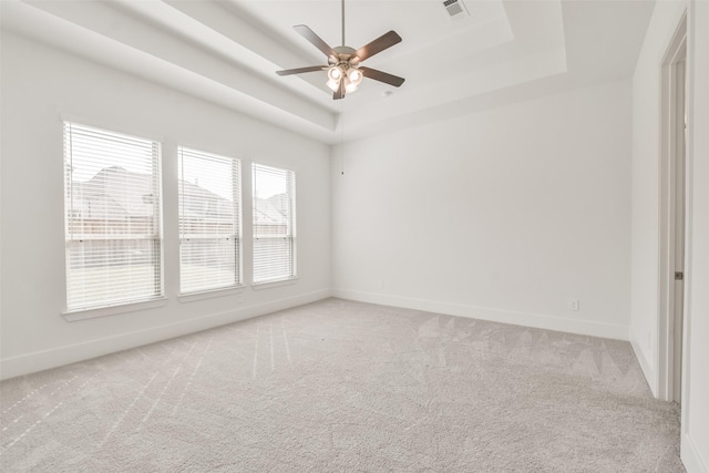 spare room with a raised ceiling, baseboards, visible vents, and carpet floors