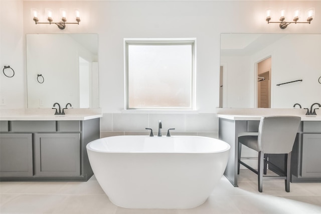 bathroom with tile patterned floors, a freestanding tub, and two vanities