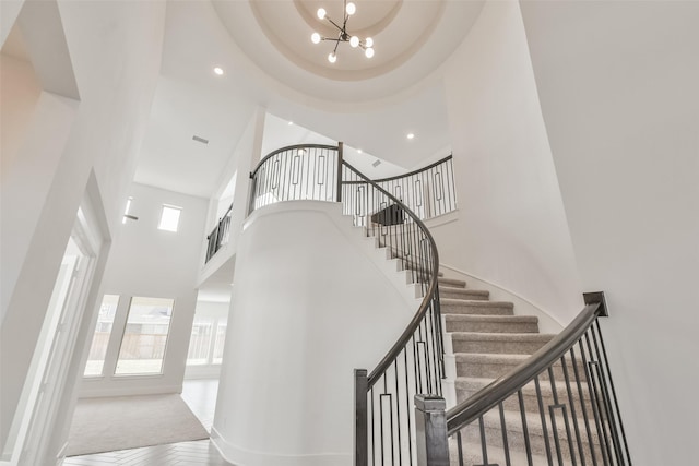 stairway with recessed lighting, a high ceiling, a healthy amount of sunlight, and an inviting chandelier