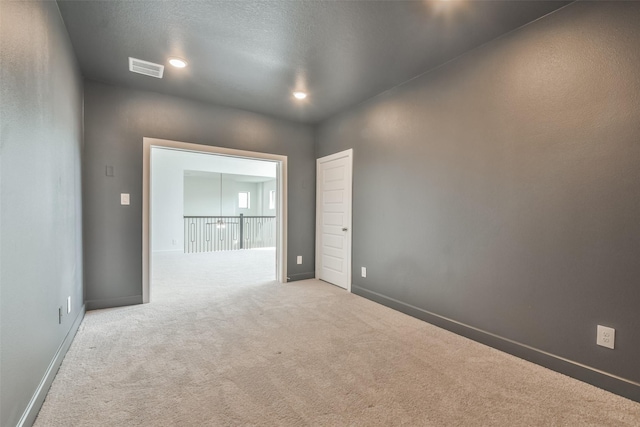 empty room with baseboards, visible vents, carpet floors, and a textured ceiling