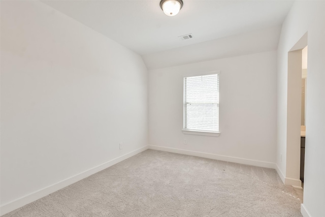 empty room with light carpet, visible vents, baseboards, and lofted ceiling