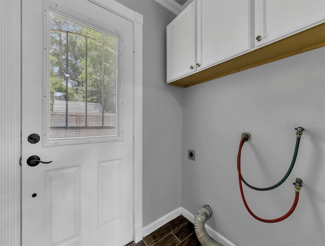 washroom featuring dark wood-type flooring, cabinet space, baseboards, and a wealth of natural light