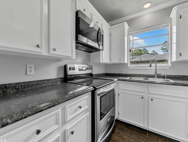 kitchen featuring wood finish floors, a sink, white cabinetry, stainless steel appliances, and crown molding