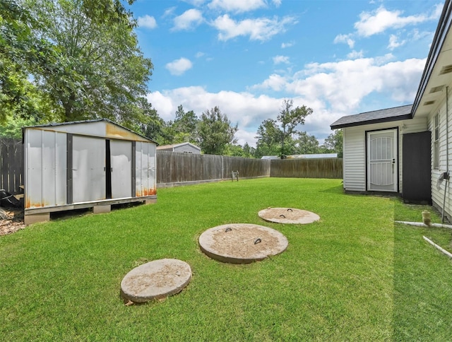 view of yard featuring a storage shed, a fenced backyard, and an outdoor structure