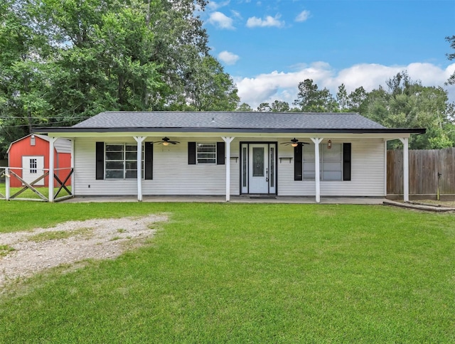 single story home featuring a front yard, fence, an outdoor structure, and ceiling fan