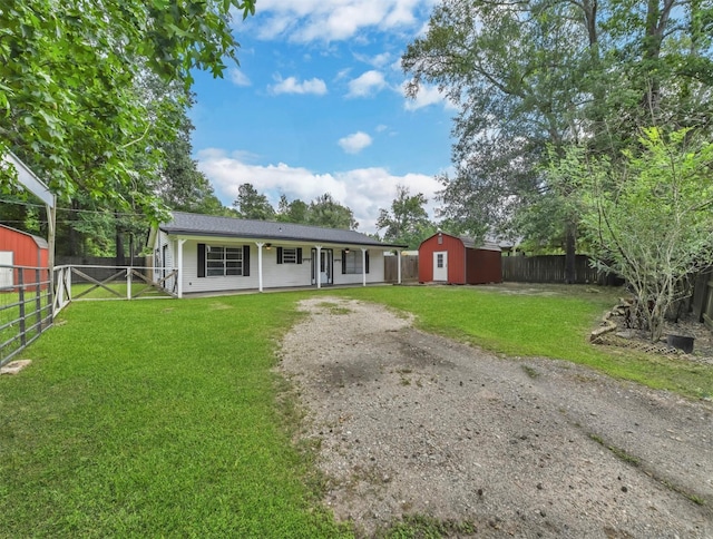 ranch-style home with a front lawn, dirt driveway, a storage shed, an outdoor structure, and a fenced backyard