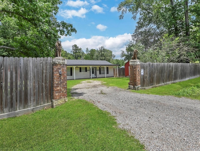 single story home with fence private yard, gravel driveway, and a front lawn